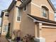 Charming two-story home featuring a tan exterior, a two-car garage, and well-manicured landscaping at 3772 Huntwicke Blvd, Davenport, FL 33837