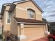 Charming two-story home featuring a tan exterior, a two-car garage, and well-manicured landscaping at 3772 Huntwicke Blvd, Davenport, FL 33837