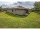 View of the backyard of a stucco house with a grassy lawn and covered porch at 543 Nardello Dr, Deltona, FL 32725