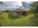View of the backyard of a stucco house with a grassy lawn and covered porch at 543 Nardello Dr, Deltona, FL 32725