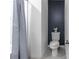 Well-lit bathroom with toilet next to navy accent wall and shower with curtain at 543 Nardello Dr, Deltona, FL 32725
