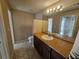 Standard bathroom with tan walls, tile flooring, light-toned countertops, and a large mirror reflecting an open doorway at 5525 Pga Blvd # 4611, Orlando, FL 32839