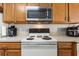 A close up of a kitchen featuring a white range below a stainless steel microwave oven at 725 Cresting Oak Cir # 117, Orlando, FL 32824