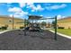 A playground featuring a swing set, playground equipment, a shade structure, and dark mulch ground covering at 725 Cresting Oak Cir # 117, Orlando, FL 32824