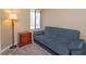 Cozy bedroom features a blue sofa bed, accent table with a lamp, and a bright window at 7254 Della Dr, Orlando, FL 32819