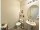 Simple and clean half bathroom with a pedestal sink, round mirror, and neutral decor at 9040 Alba Ln, Kissimmee, FL 34747