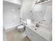 Clean, all-white bathroom featuring a tub, toilet, and vanity with a modern sink and mirror at 9345 Buttonwood St, Orlando, FL 32825