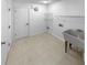 Bright laundry room with large utility sink, tile flooring, white walls, and storage shelves at 9345 Buttonwood St, Orlando, FL 32825