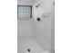 Modern shower with glass block window, tiled walls, and updated fixtures in an all white space at 9345 Buttonwood St, Orlando, FL 32825