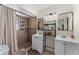 Bathroom with dual sinks, a decorative shelf, and a shower with tile surround and neutral-toned curtain at 9911 Dean Cove Ln, Orlando, FL 32825