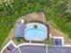 Overhead view of the community pool, surrounded by lush trees, lounge chairs, and parking at 12928 Lexington Summit St, Orlando, FL 32828