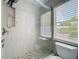 This is a clean bathroom with a tile shower and a toilet with a bright window at 10105 Dean Point Pl, Orlando, FL 32825