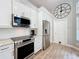 A modern kitchen features white cabinets, granite countertops, stainless steel appliances, and wood-look floors at 10105 Dean Point Pl, Orlando, FL 32825