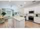 A modern kitchen boasts white cabinets, stainless steel appliances, an island, and wood flooring that flows into the living room at 10105 Dean Point Pl, Orlando, FL 32825