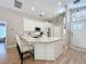 A modern kitchen with wood floors, white cabinets, a large island, and barstool seating for stylish and functional design at 10105 Dean Point Pl, Orlando, FL 32825