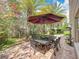 Cozy backyard paver patio featuring an umbrella-covered dining set, mature trees and private landscaping at 10105 Dean Point Pl, Orlando, FL 32825