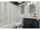 This is a bright bathroom featuring a shower-tub combo, dark blue vanity, and decoratively framed mirror at 111 Crown Oaks Way # 101, Longwood, FL 32779