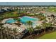 Aerial view of a community pool with lounge chairs, palm trees, splashpad, and a pergola covered dining area at 11456 Short Story St, Orlando, FL 32832