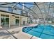 A screened-in pool features stone trim and backyard views from the sliding glass doors at 1302 Shelter Rock Rd, Orlando, FL 32835
