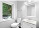 Bright bathroom featuring a toilet, vanity with sink, and a window with a view of trees at 1415 Brumley Rd, Chuluota, FL 32766