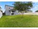 Large grassy backyard enclosed by white fencing with a covered patio, and mature tree at 15210 Montesino Dr, Orlando, FL 32828