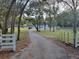 Long paved driveway leads to this country estate with a white fenced in yard and mature trees at 16742 Se 165Th Ave, Weirsdale, FL 32195