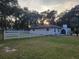 Exterior view of home featuring white stucco, fenced in yard, and porte cochere at 16742 Se 165Th Ave, Weirsdale, FL 32195