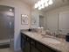 Bright bathroom featuring double sinks with granite countertops, modern lighting, and a glass-enclosed shower at 197 Jetty Way, Davenport, FL 33897