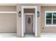 Close-up showcasing an inviting front door with decorative glass and stylish lanterns on the neutral facade at 2065 East Pkwy, Deland, FL 32724