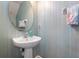 Compact bathroom with a pedestal sink, round mirror, and decorative elements, perfect for guests and convenient powder room at 2803 Boating Blvd, Kissimmee, FL 34746