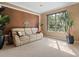 Cozy living room with a comfortable sofa, plants, and a large window offering a view of the landscaped yard at 2803 Boating Blvd, Kissimmee, FL 34746