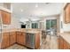 Well-lit kitchen area with wood cabinets, stainless steel dishwasher, and view of the dining and living room at 2906 Sunset Vista Ct, Kissimmee, FL 34747