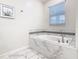 Bright bathroom features a soaking tub with tile surround and a window at 303 Ocean Course Ave, Davenport, FL 33896