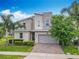 Contemporary two-story home with stone accents, paver driveway, and lush tropical landscaping at 303 Ocean Course Ave, Davenport, FL 33896