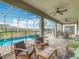 Screened in patio with comfortable seating around a pool and spa, overlooking backyard at 303 Ocean Course Ave, Davenport, FL 33896