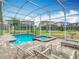 Inviting pool and spa surrounded by lounge chairs and enclosed with a screened enclosure at 303 Ocean Course Ave, Davenport, FL 33896