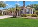 Beautifully landscaped single-Gathering home featuring a brick driveway and lush green lawn, with palm trees and colorful flower beds at 453 Kays Landing Dr, Sanford, FL 32771
