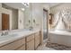 Bright bathroom featuring dual sinks, neutral cabinets, tub, and glass-enclosed shower at 4561 Heritage Oak Dr, Orlando, FL 32808