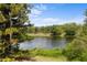 Scenic lake view framed by lush greenery and mature trees under a blue sky at 4561 Heritage Oak Dr, Orlando, FL 32808