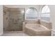 Bathroom featuring a glass shower and a soaking tub with arched windows at 603 Yorkshire Dr, Oviedo, FL 32765