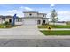 Modern two-story home with a pristine white exterior, manicured lawn, and a spacious driveway at 6454 Chorus Dr, Mascotte, FL 34753