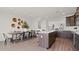 A dining area and kitchen features a large island, dark cabinets, stainless steel appliances, and wood flooring at 6678 Juneberry Way, Winter Garden, FL 34787