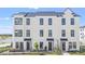 A modern three-story townhome with a white facade, black windows, and well-maintained landscaping at 6678 Juneberry Way, Winter Garden, FL 34787
