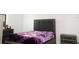 Cozy bedroom with a stylish upholstered bed, matching nightstands, and a purple floral blanket at 707 Staffora St, Haines City, FL 33844