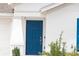 Close-up of a blue front door with a white frame, complemented by modern hardware and manicured landscaping at 707 Staffora St, Haines City, FL 33844