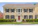 Two-story tan home with black shutters, red door, manicured landscaping, and an inviting entrance at 754 Centervale Dr, Kissimmee, FL 34747