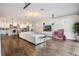 Bright living room features hardwood floors, a comfortable white sofa, and seamless flow into the kitchen at 9443 Merrifield St, Orlando, FL 32827