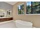 Bright bathroom featuring a modern soaking tub, stylish vanity, and large windows at 9743 Covent Garden Dr, Orlando, FL 32827
