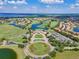 Scenic aerial view of a community featuring a golf course, ponds, and lush landscaping, under a blue sky with clouds at 10533 Belfry Cir, Orlando, FL 32832