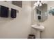 Stylish powder room featuring a pedestal sink, decorative mirror, and modern fixtures at 10533 Belfry Cir, Orlando, FL 32832